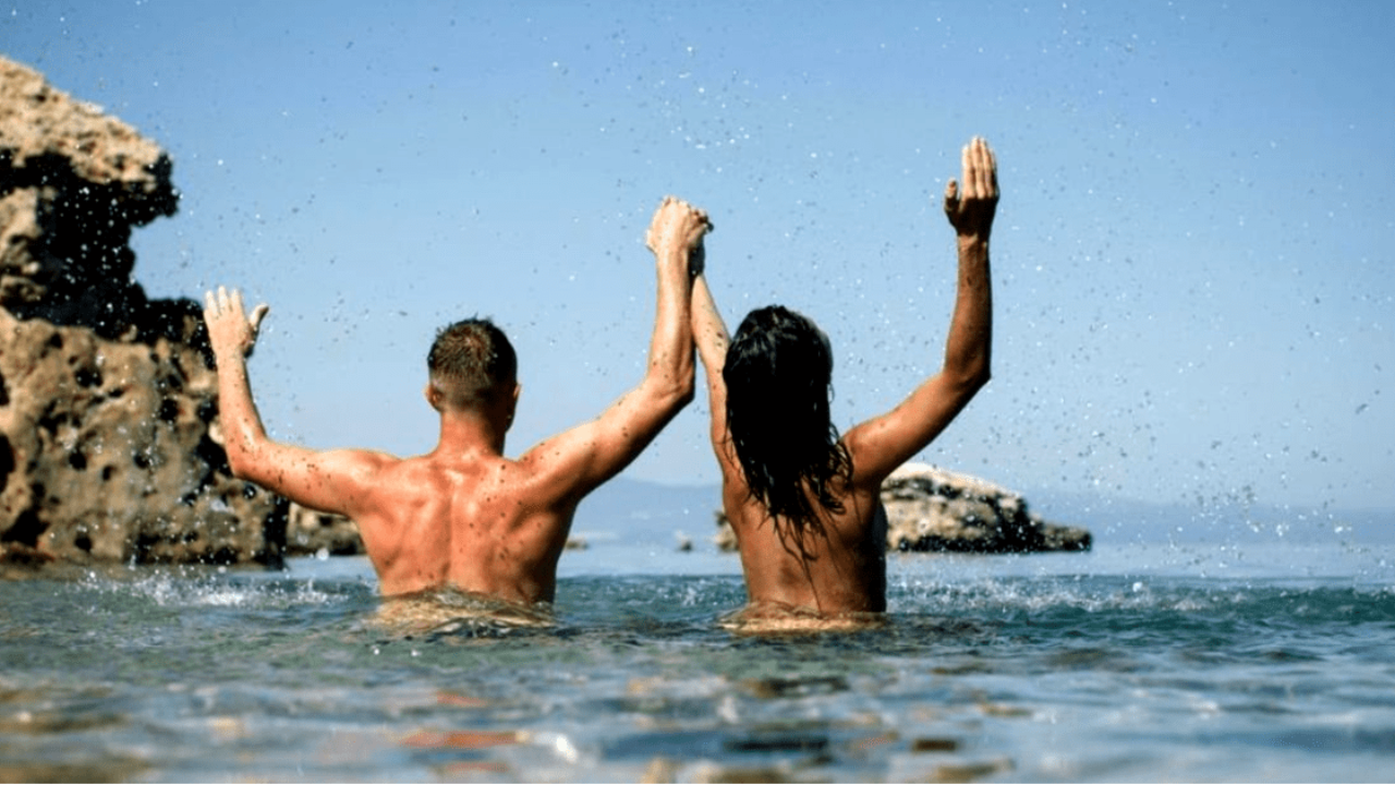 Topless ladies surrounded by dressed men at the beach